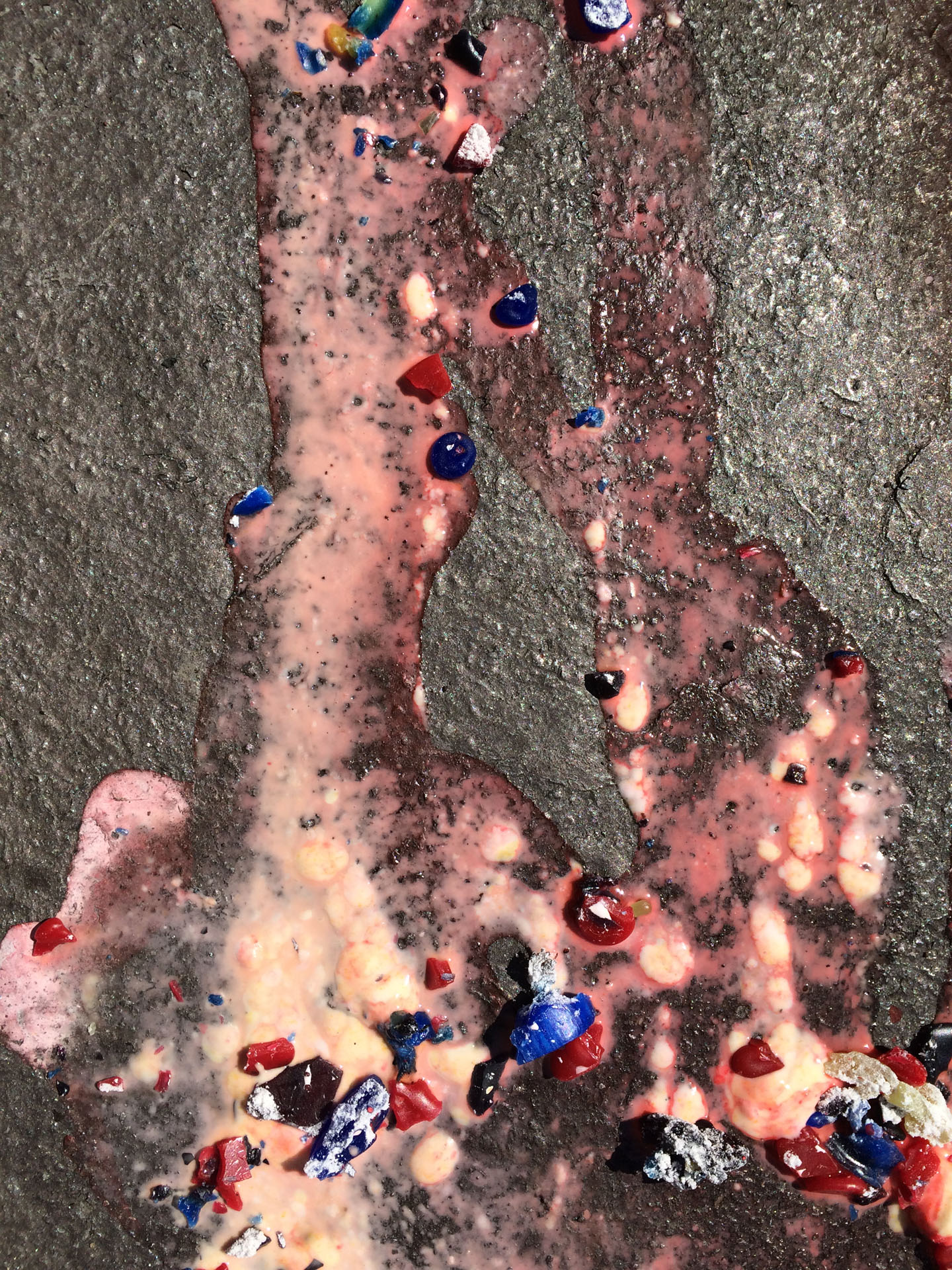 A stream of gloopy pink liquid with some colourful fragments in it